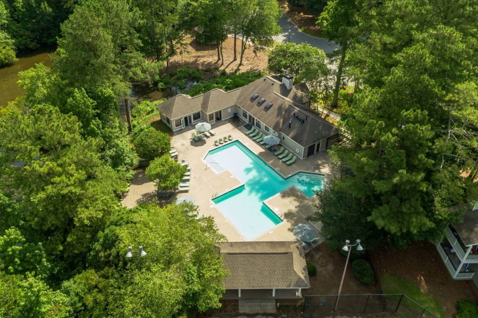 An aerial view of a pool surrounded by trees at the 42 Apartment Property Management.