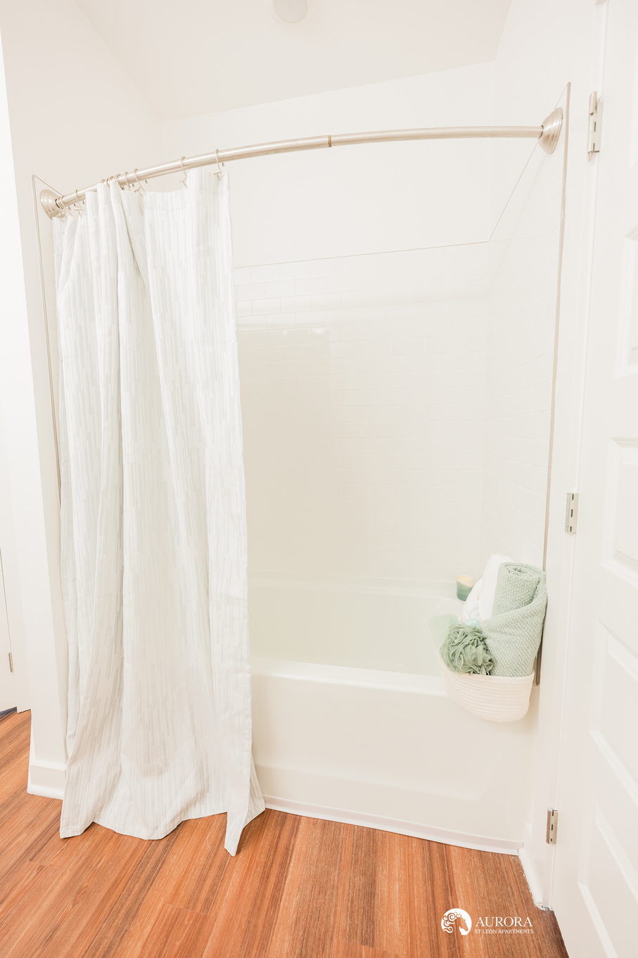 A bathroom with a white shower curtain and wooden floors in a 42 Apartment Property Management.
