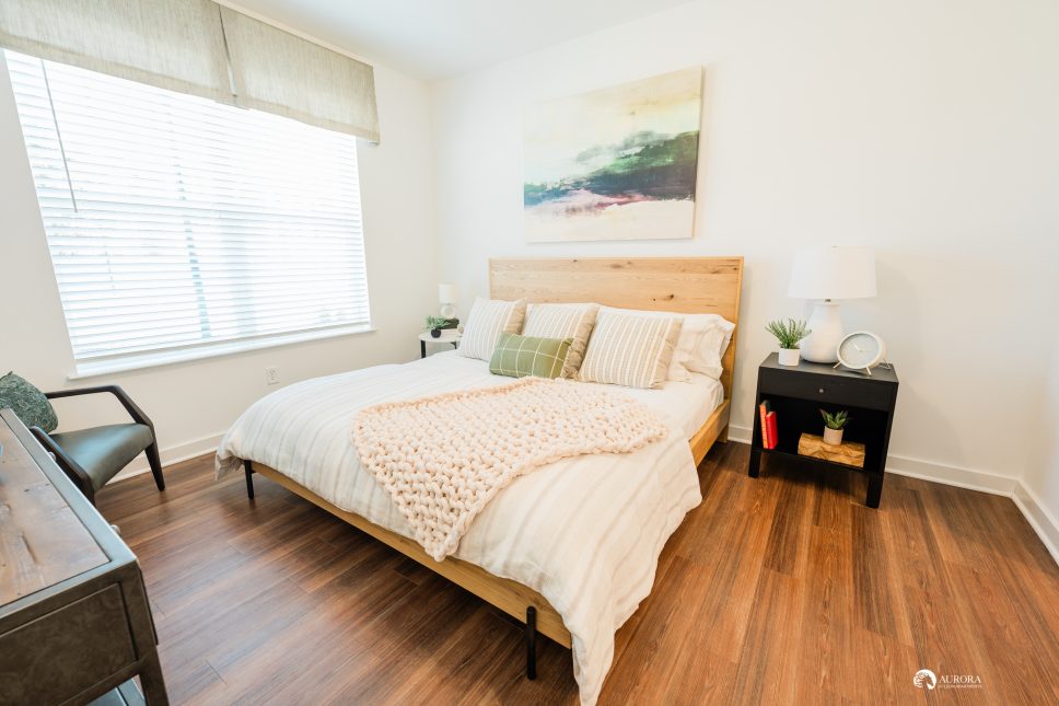 A bedroom with hardwood floors and a painting on the wall in a 42 Apartment Property Management building.
