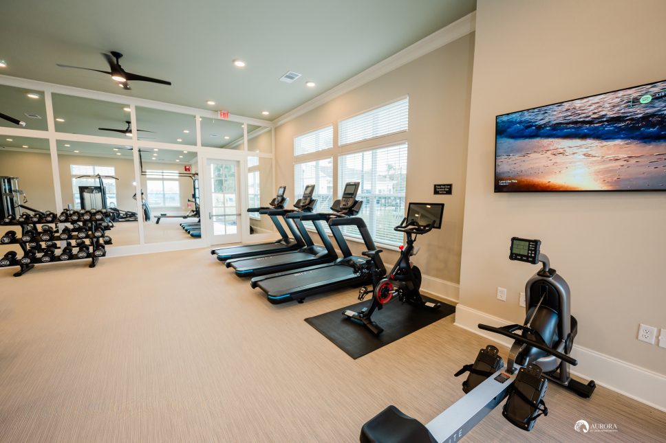 A gym at the 42 Apartment Property Management with tread machines and a TV.