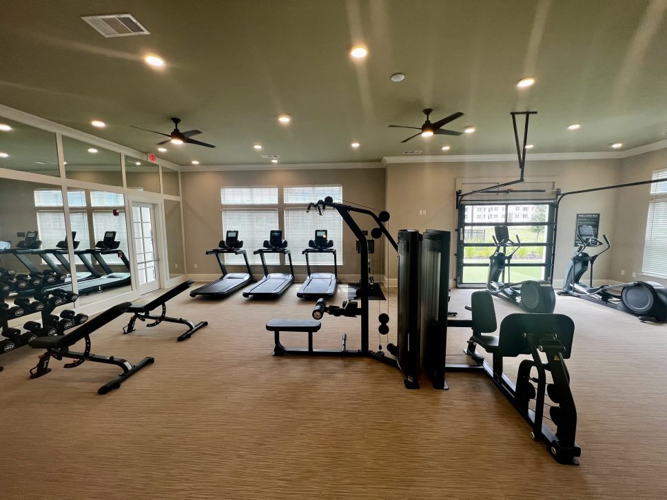 A gym room with exercise equipment and a ceiling fan in a 42 Apartment Property Management property.