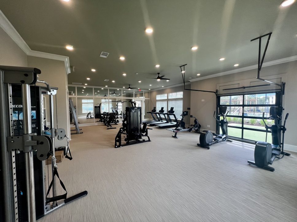 A gym room with exercise equipment and a sliding glass door, available at 42 Apartment Property Management.