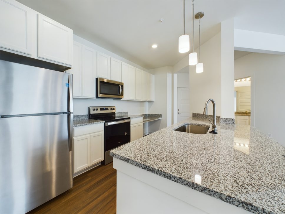 A kitchen with stainless steel appliances and granite counter tops that complements the aesthetic of 42 Apartment Property Management.