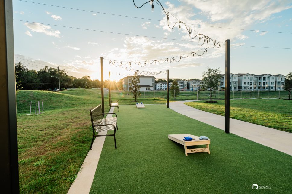 A park with benches and a corn hole game, managed by 42 Apartment Property Management.