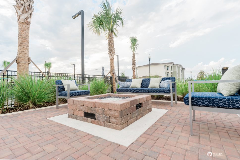 A patio with a fire pit and blue furniture in an apartment complex managed by 42 Property Management.