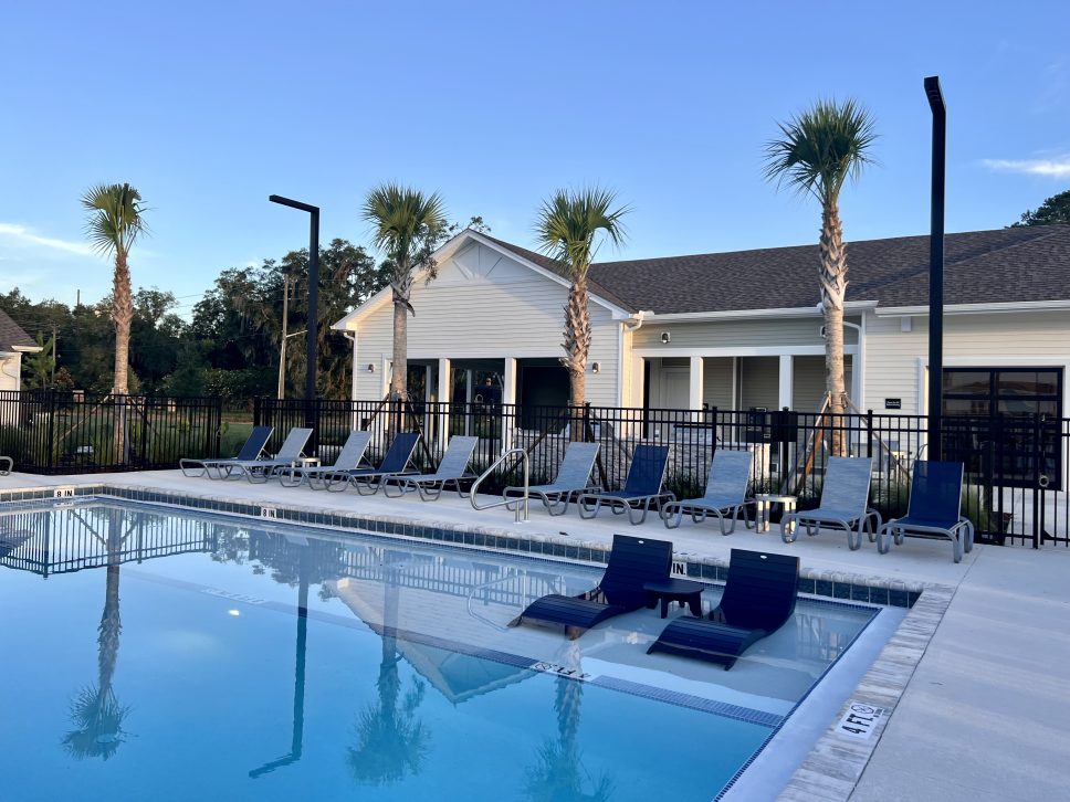 A swimming pool with lounge chairs and palm trees managed by 42 Apartment Property Management.