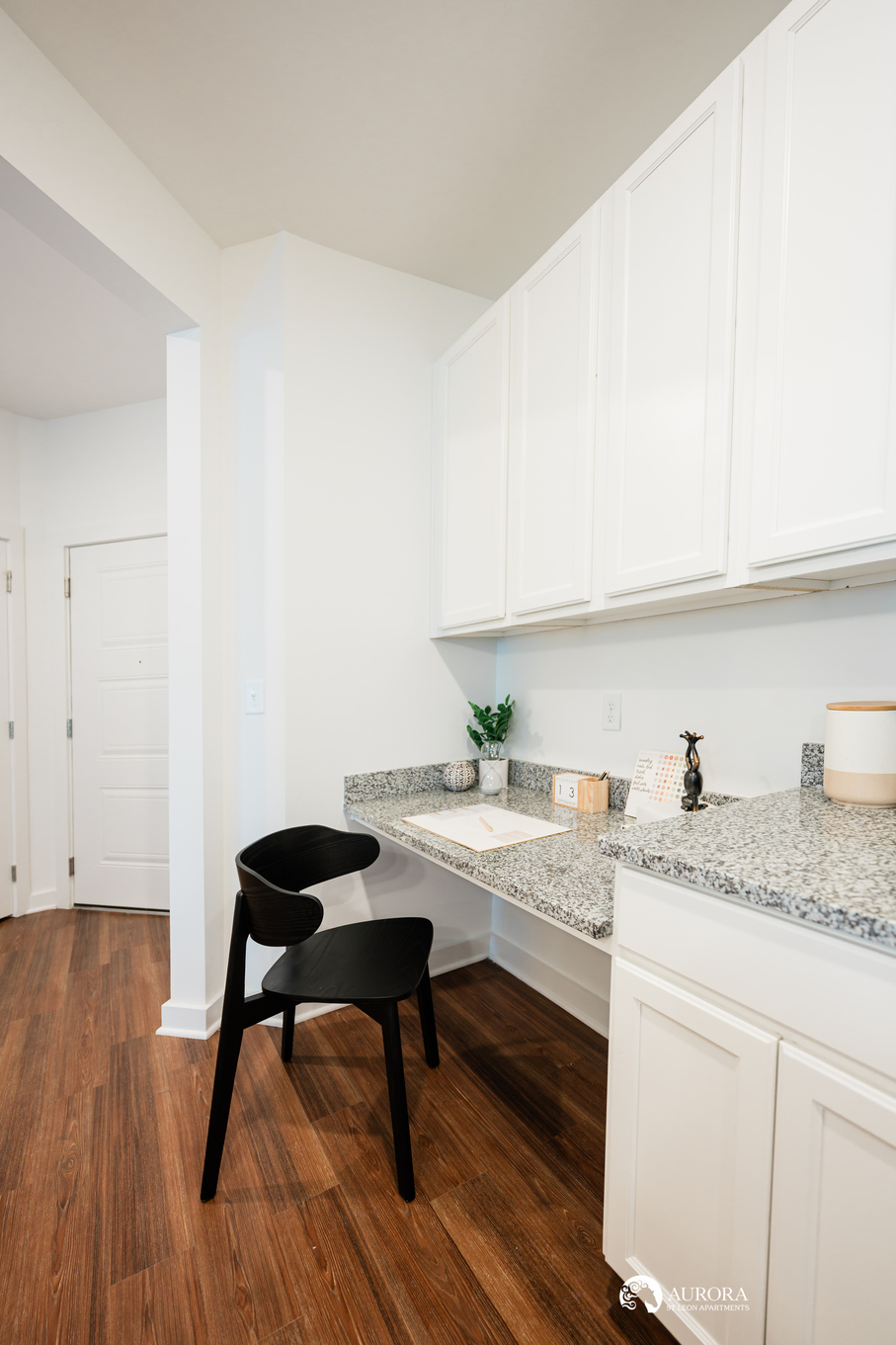 A white kitchen with a black chair and hardwood floors, located in a 42 Apartment property managed by Property Management.