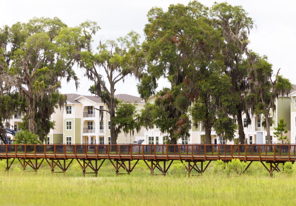 A wooden bridge over a grassy area within a 42 apartment property management.