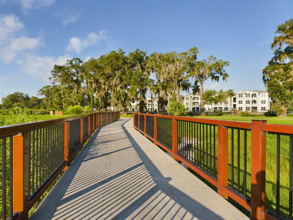 A wooden walkway leading to a grassy area managed by 42 Apartment Property Management.