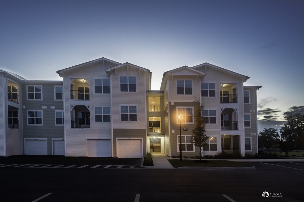An apartment building at dusk in a parking lot managed by 42 Apartment Property Management.