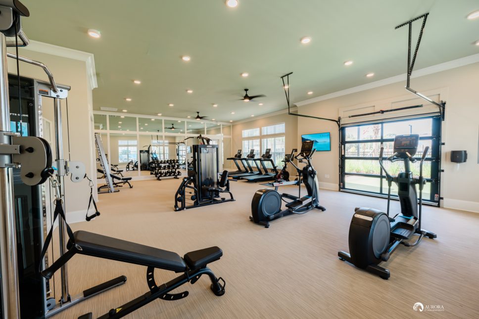 An apartment gym room with exercise equipment and a sliding glass door managed by 42 Apartment Property Management.