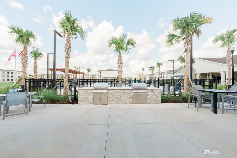 An outdoor area with palm trees and a grill, managed by 42 Apartment Property Management.