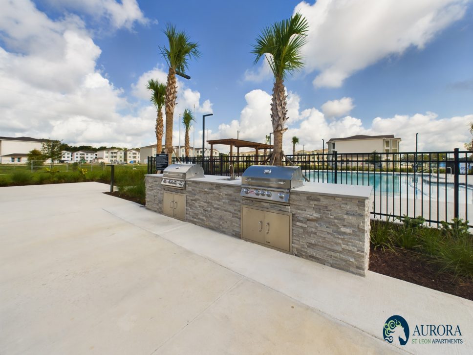 The 42 apartment property management provides BBQ grills in a pool area with palm trees.