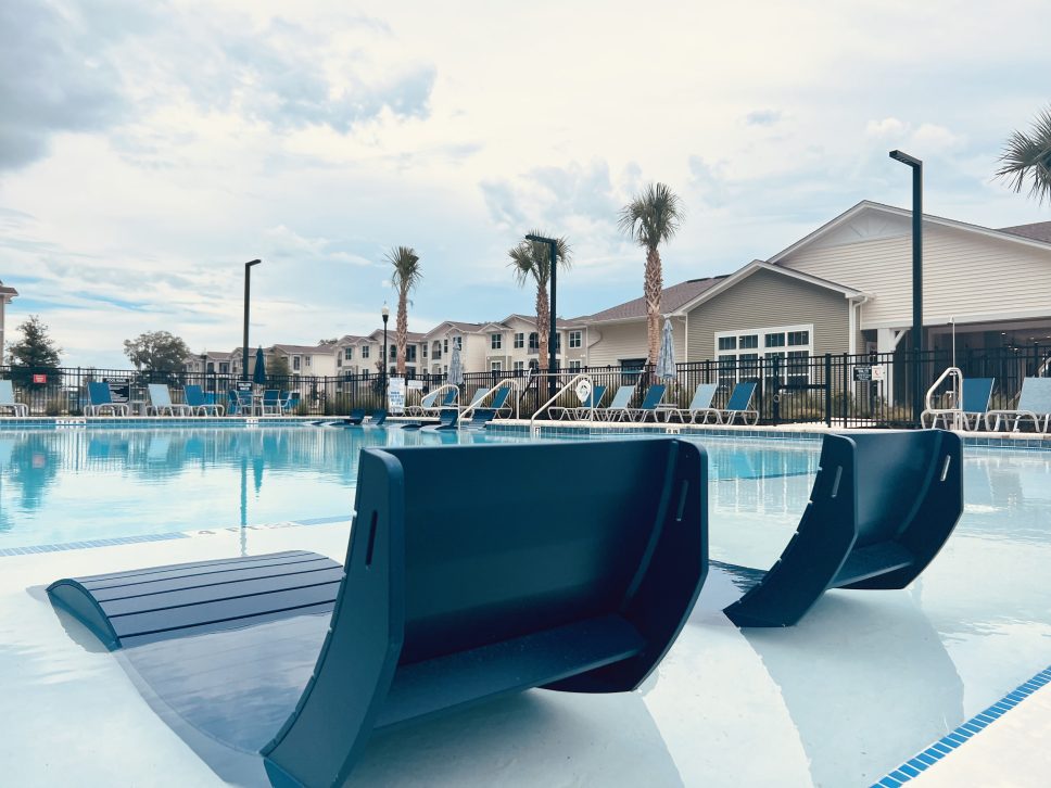 Two blue lounge chairs by the swimming pool in a 42 Apartment Property.